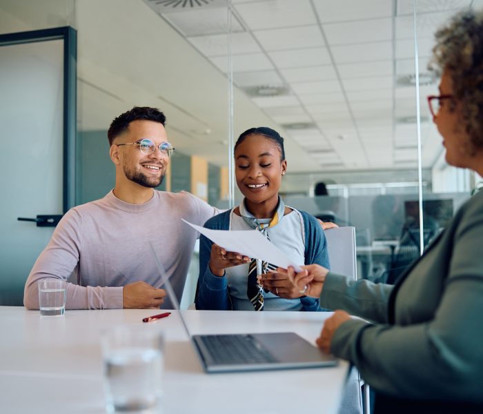 Young multiracial couple and their financial advisor going through paperwork during a meeting in the office.